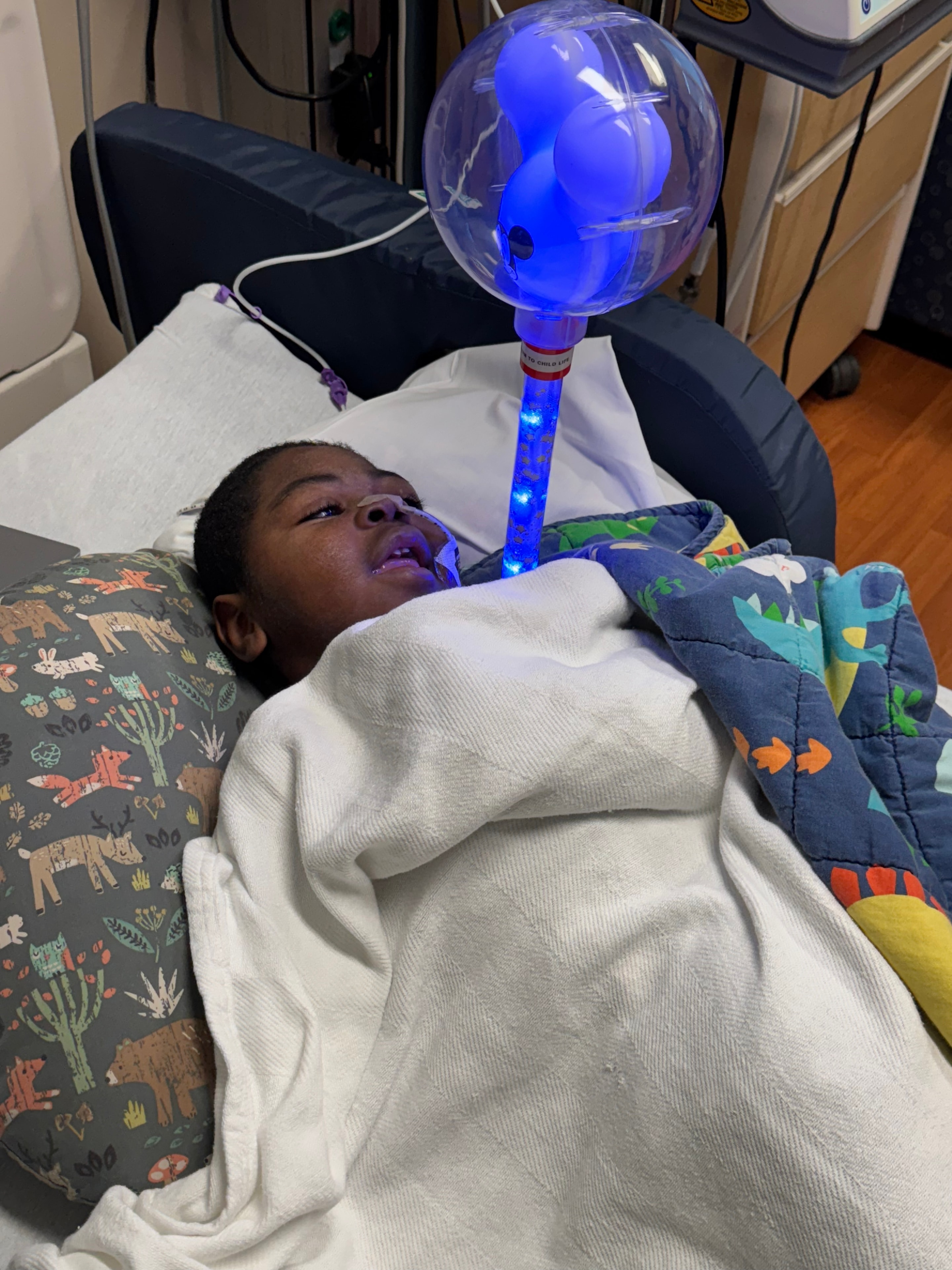 Myles watching a glowing blue light toy in the hospital