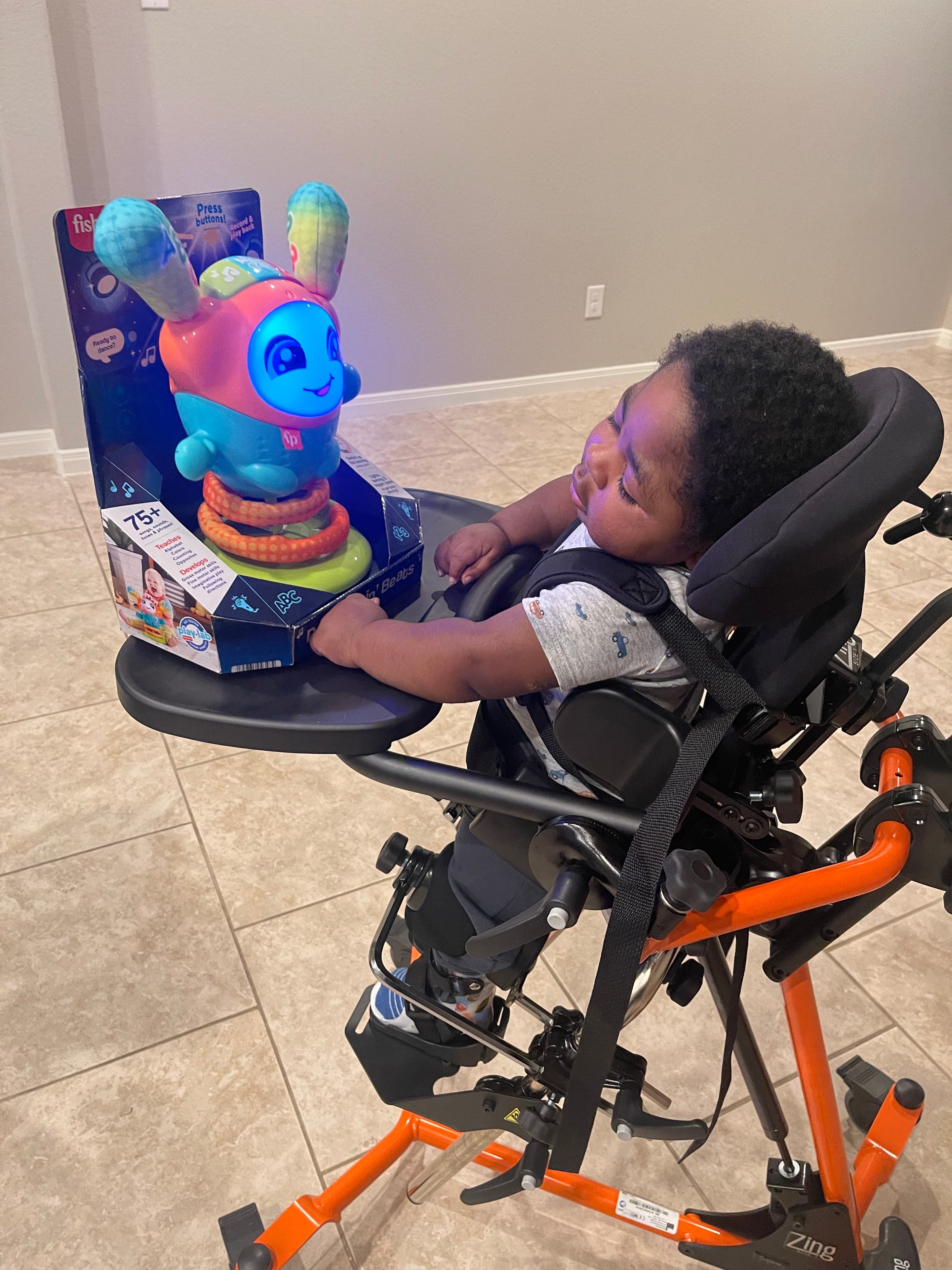 Myles in his stander next to a colorful light-up toy